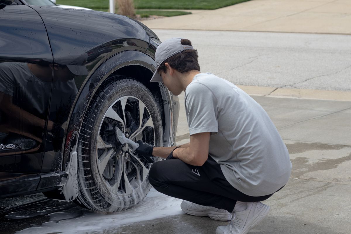 Hand-scrubbing a soapy wheel during a detailing job