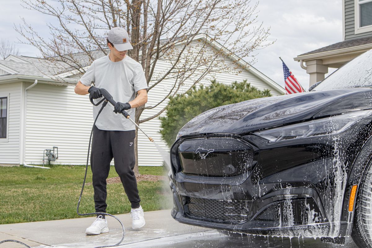 Pressure-washing a black Mustang Mach-E during a mobile detail